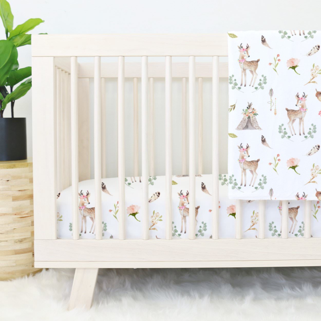 تخت خواب نوزاد چوبی که دارای روتختی با طرح زیبا و آهو می باشد